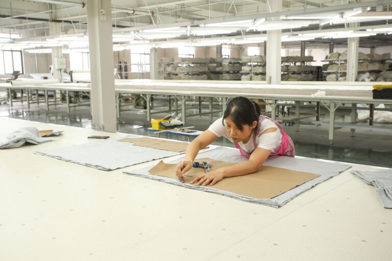 A worker reviewing a paper pattern at a worktable