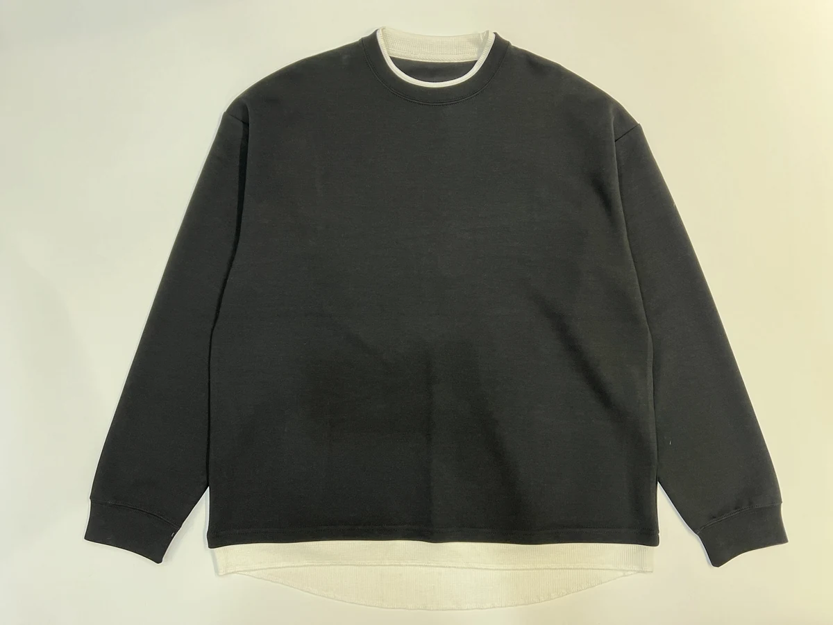 Black crewneck sweatshirt laid flat on a pale background