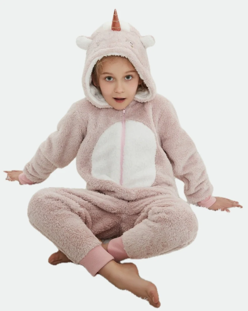 Child seated on a rug wearing a pink-and-white hooded unicorn onesie