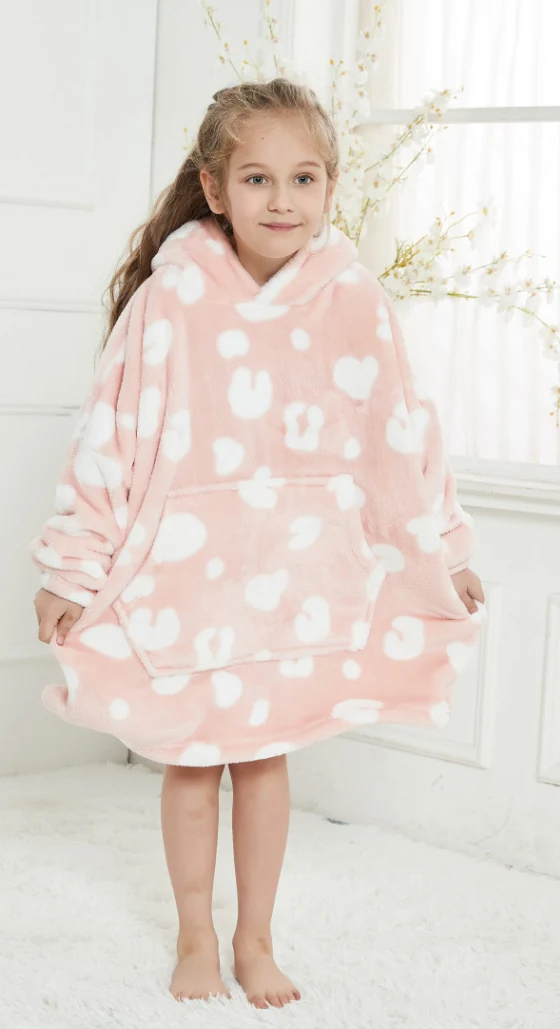 Child wearing a loose pink heart-print hooded blanket with a front pocket