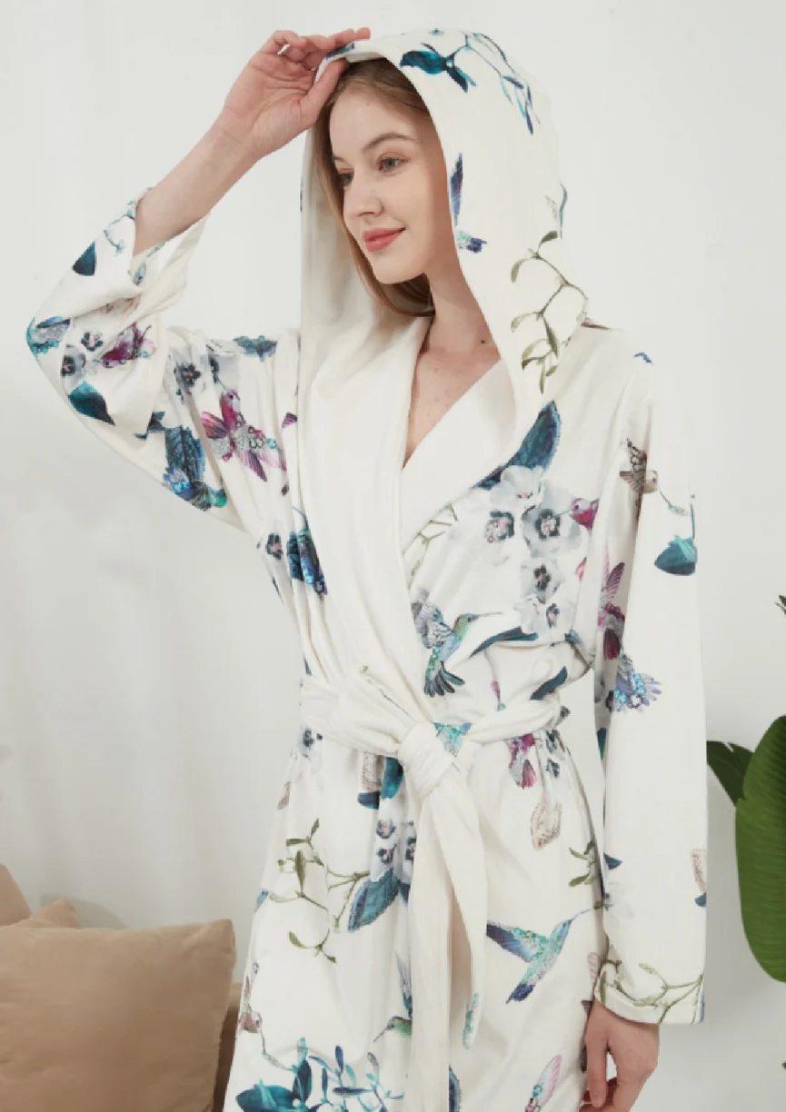 Woman wearing a light floral-print hooded robe with a tied belt