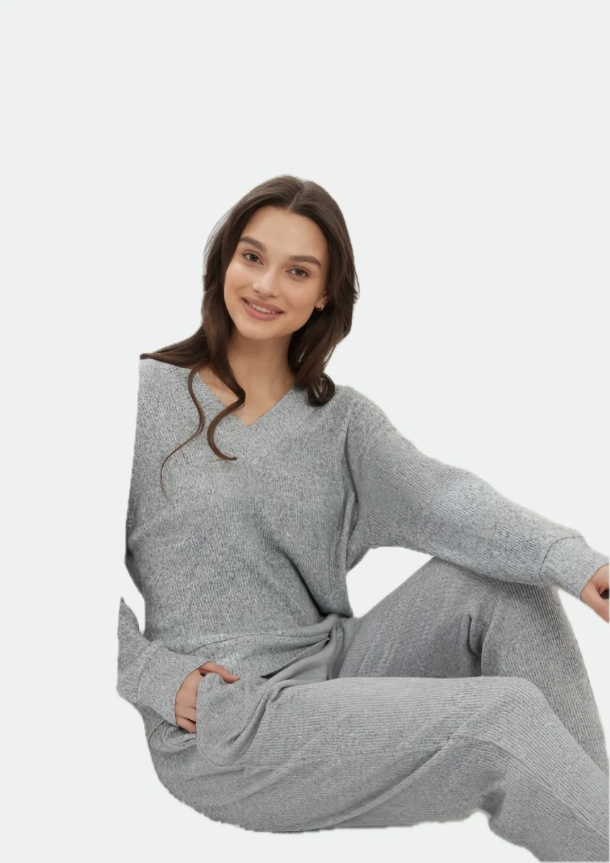 Woman seated on a pale sofa wearing a grey long-sleeve lounge set